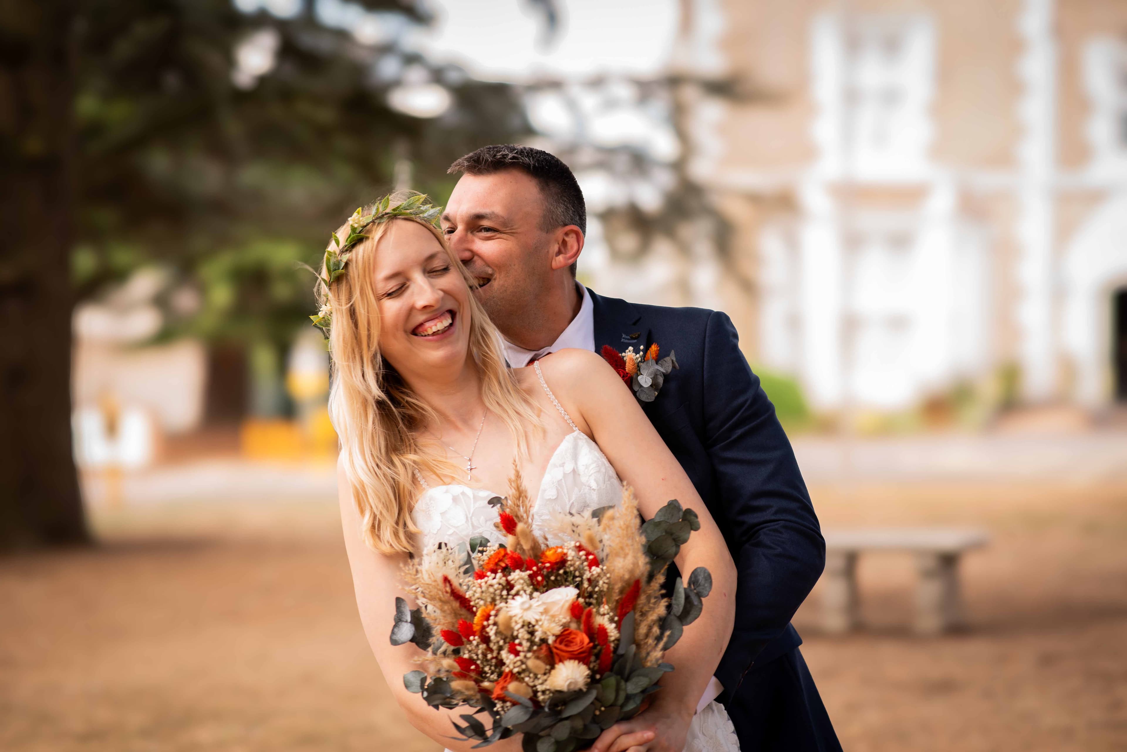 Bride laughing joyfully as her groom embraces her from behind