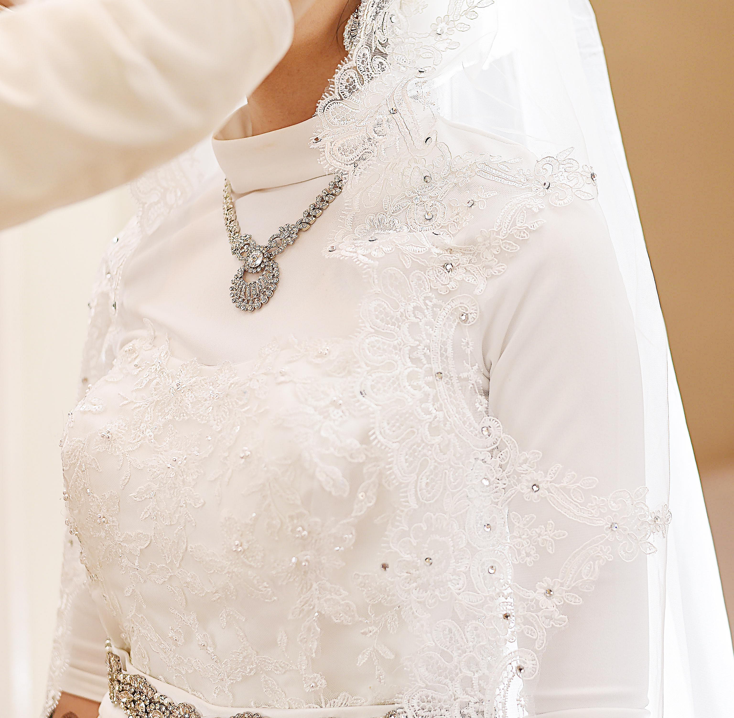 Elegant bride being dressed by her mother in radiant natural light