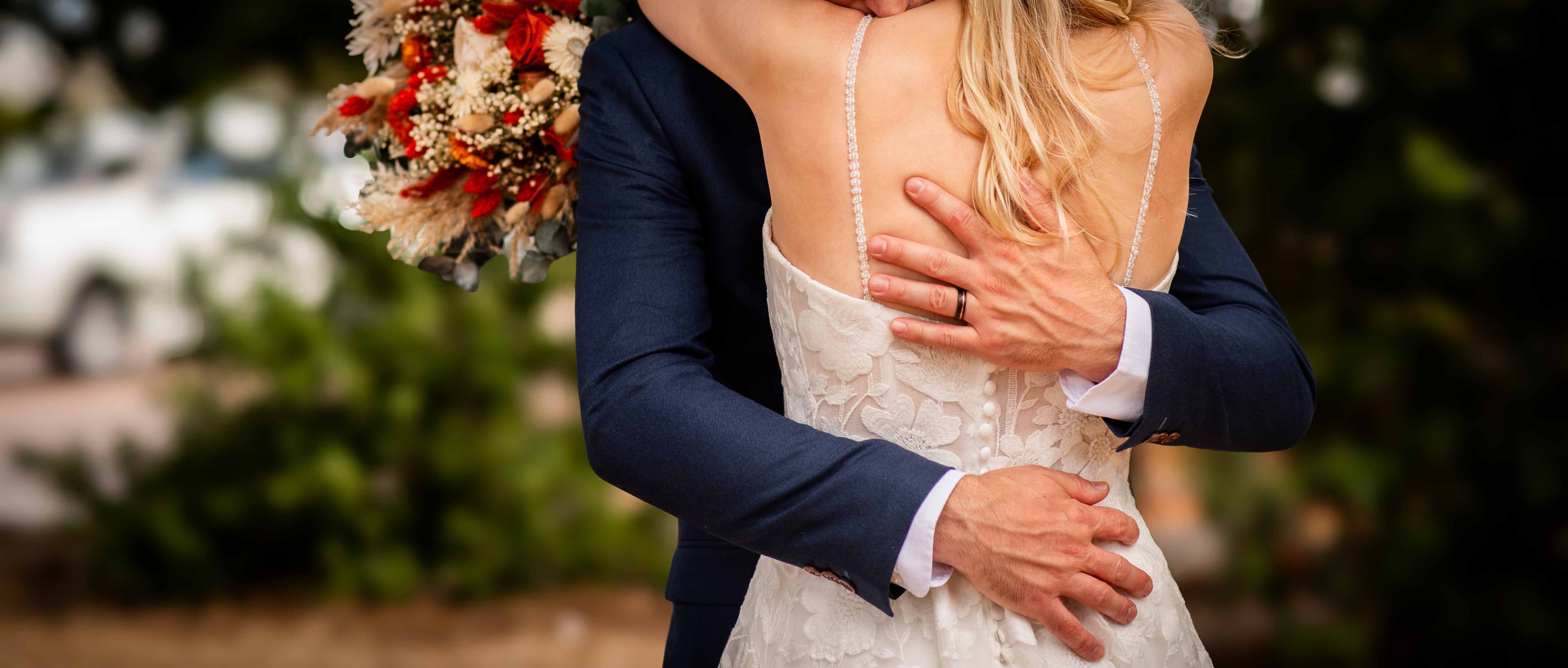 Groom's hands resting on his bride's back as they embrace