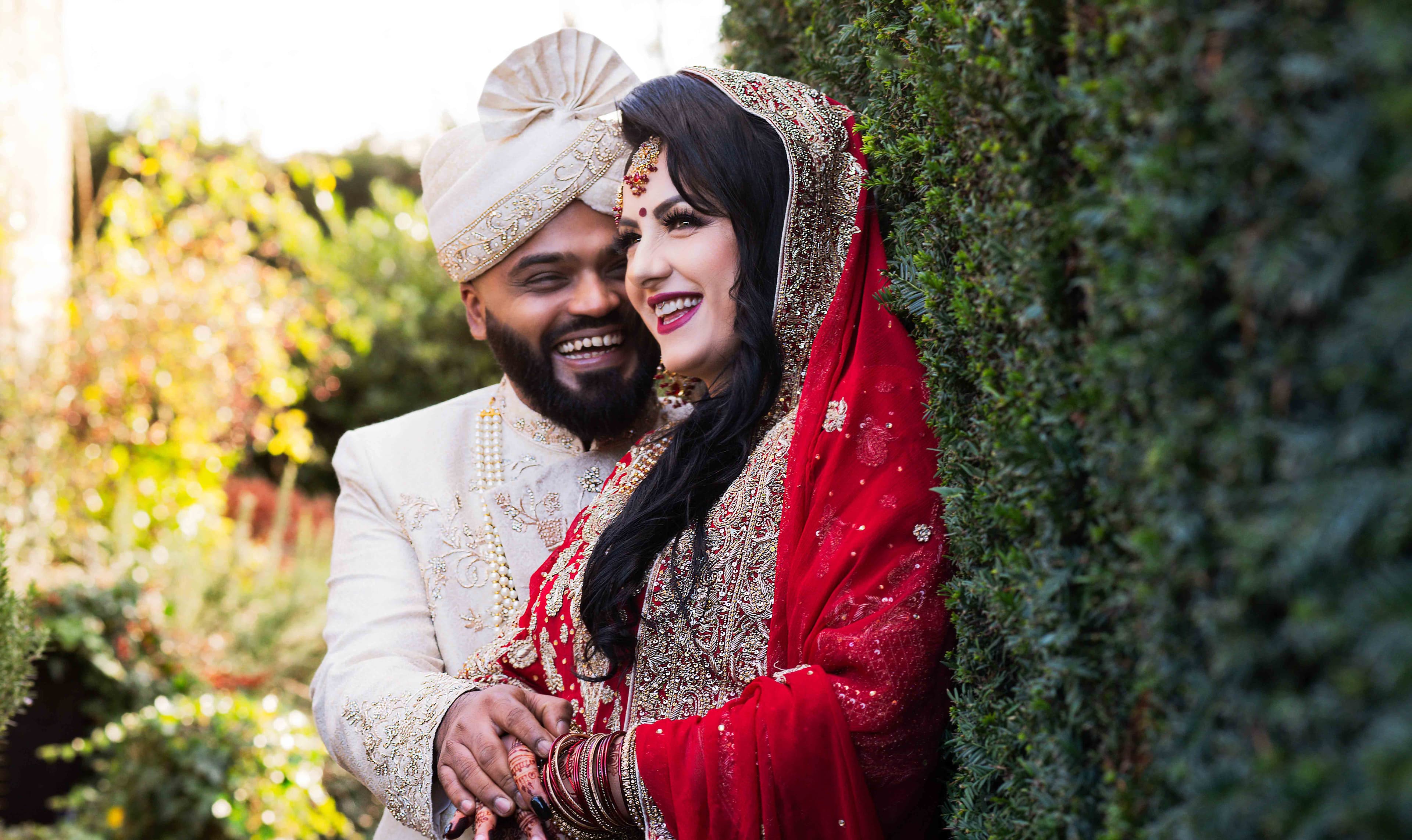 The bride and groom laugh together in the lush gardens of Kent
