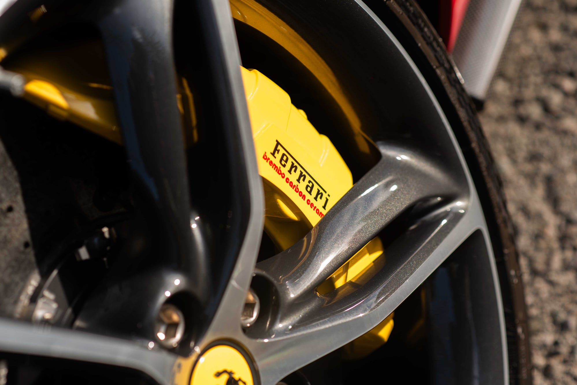 Ferrari 296 GTB Brembo carbon ceramic brake caliper behind a grey alloy wheel